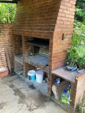 A brick-built outdoor oven with a shelf, two buckets, and a canister.