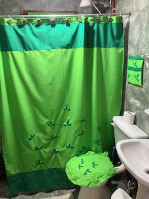A bathroom with a green shower curtain, a white sink, and a toilet.