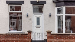 A two-story house with a white front door, a number '86' above the door, and a small balcony with a black wrought iron railing. - Sunderland City Stay Secure Parking Sleeps 4 (Sunderland)