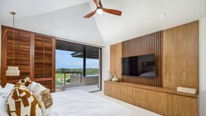 A bedroom with a bed, wooden paneling, a TV, and a view of the outdoors. - New Family Luxury Golf Penthouse With Private Pool (Punta de Mita)