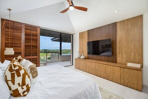 Ein Schlafzimmer mit Bett, Holzvertäfelung, Fernseher und Blick ins Freie.