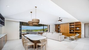 A modern living space with a dining area, sofa, and built-in wooden shelving. - New Family Luxury Golf Penthouse With Private Pool (Punta de Mita)