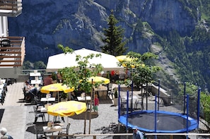 An outdoor seating area with tables and chairs, surrounded by a mountain view. - Edelweiss (Lauterbrunnen)