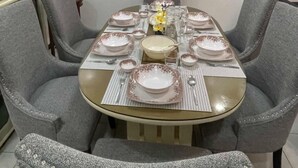 A dining area with a table set for four, grey upholstered chairs, and a ceiling fan.