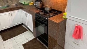A kitchen with white cabinets, a gas stove, a microwave, and a sink.