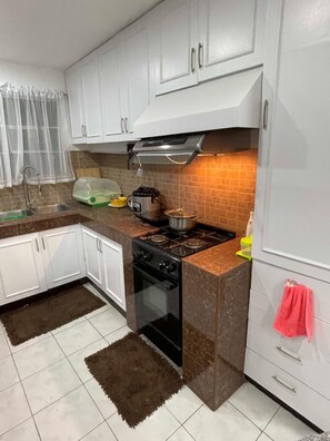 A kitchen with white cabinets, a gas stove, a microwave, and a sink.