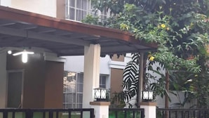 A residential building with a covered porch, a gated entrance, and a large tree with yellow flowers.