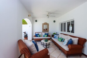 Ein Wohnzimmer mit Rattanmöbeln, Deckenventilator und einem großen Spiegel.