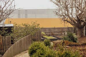Un jardí amb una tanca de fusta, un arbre i llits de jardí elevats.