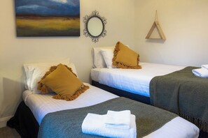 Ein Hotelzimmer mit zwei Betten, jeweils mit weißer Bettdecke und braunem Kopfkissen. An der Wand hängt ein Spiegel und über den Betten ein Bild.