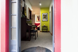 Ein Flur mit einem Klavier, einem roten Sessel und einem gerahmten Bild an der Wand.