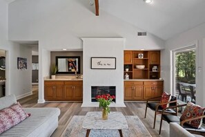 A spacious living area with a fireplace, wooden cabinets, and a dining area. - Fabulous 3-Bdrm Beach Home, Short Walk from Beach with Beautiful Golf Views (Hilton Head Island)