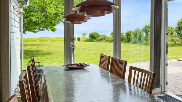 Een eettafel met stoelen, een vaas met bloemen en een schaal fruit.