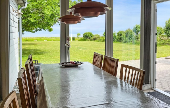 A dining table with chairs, a vase with flowers, and a bowl of fruit.