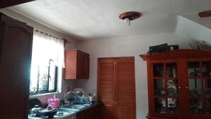 Eine Küche mit Fenster, Spüle, Schränken und einem Holzschrank mit Glastüren.