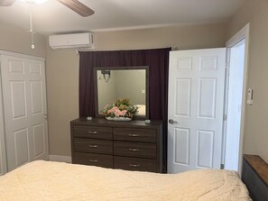 Un dormitorio con cama, cómoda, espejo y ventilador de techo.