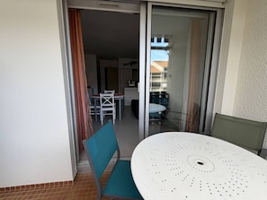 Un balcon avec une porte-fenêtre coulissante, une table et des chaises.
