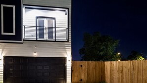 A modern two-story house with a garage, a well-maintained lawn, and a wooden fence. - Comfy Modern Getaway10mins from downtown (Houston)
