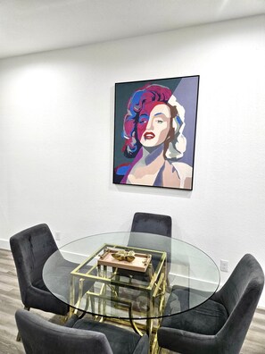 Ein moderner Essbereich mit einem Glastisch, schwarzen Stühlen und einem gerahmten Kunstwerk an der Wand.