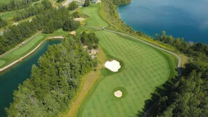 En golfbana med sandbunkrar, vattenhinder och tät vegetation.