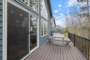 Een terras met een tafel, stoelen, een schuifpui en een balustrade.