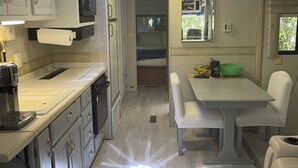 Eine kleine Küchenzeile in einem Wohnmobil mit Mikrowelle, Spüle und Essbereich.