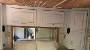 Ein Schlafzimmer mit Holzbalkendecke, weißen Wänden, einem Bett mit weißer Bettwäsche und einem kleinen Nachttisch.