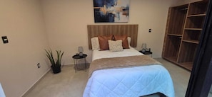 A bedroom with a bed, bedside tables, a nightstand, a potted plant, a painting on the wall, and a wooden wardrobe.