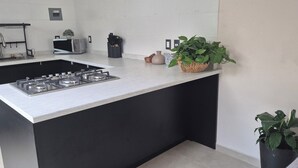 Une cuisine moderne dotée d’un îlot central, d’un four à micro-ondes et d’une cuisinière à gaz.