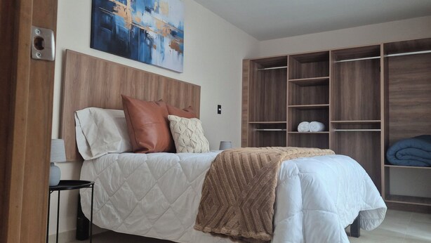 Une chambre à coucher avec un lit, une table de chevet, une tête de lit en bois, une armoire et un tableau au mur.