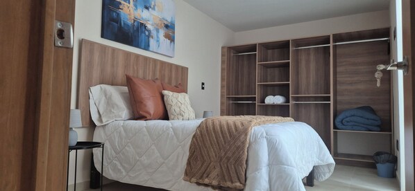 A bedroom with a bed, a nightstand, a wooden headboard, a wardrobe, and a painting on the wall.