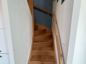 Una escalera de madera con barandilla que conduce a un rellano con una puerta.