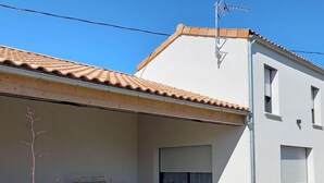 Een gebouw met een pannendak, een witte gevel en een zichtbare antenne.