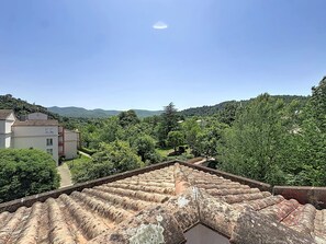 Ein mit Terrakotta-Ziegeln gedecktes Dach, ein Weg und ein Blick auf eine grüne Landschaft mit Bäumen und Hügeln.