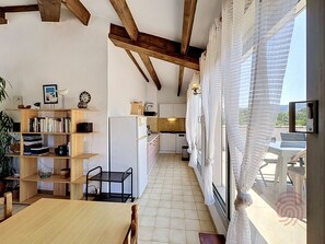 Una cocina con vigas de madera, un refrigerador blanco y un comedor con mesa y sillas.