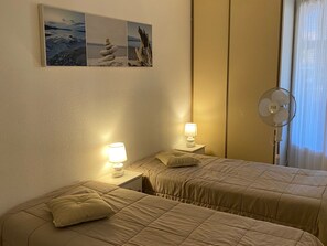 A hotel room with two beds, a standing fan, and a wall-mounted picture. - Apartment with AC, port, pets welcome - 4 guests (Port Leucate)