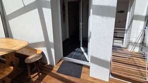 Een houten tafel en stoelen voor een gebouw met een deur naar binnen.