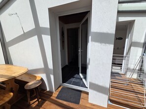 Ein Holztisch und Stühle vor einem Gebäude mit einer Tür zu einem Innenraum.