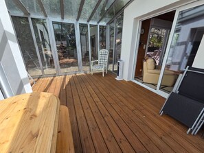 A wooden deck with a glass enclosure, a chair, and a sofa. - Spacious house near the beach - 8 guests (La Tranche-sur-Mer)