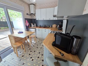 Cocina compacta con mesa de madera, un fregadero, estufa y refrigerador.