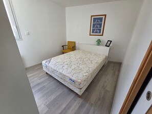 A bedroom with a bed, a chair, a lamp, and a framed picture on the wall. - Spacious house near the beach - 8 guests (La Tranche-sur-Mer)