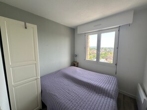A bedroom with a bed, a window, and a radiator. - Apartment with parking - 4 guests. (Cabourg)