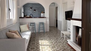 A cozy living area with a sofa, two bar stools, a fireplace, and a kitchen with a blue backsplash. - Beachfront house with stunning views - 4 guests (Denia)