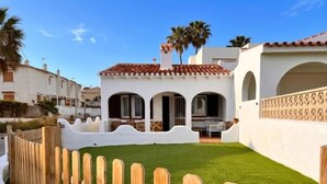 A white building with a red-tiled roof, a wooden fence, and a well-maintained lawn. - Beachfront house with stunning views - 4 guests (Denia)