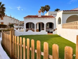 A white building with a red-tiled roof, a wooden fence, and a well-maintained lawn. - Beachfront house with stunning views - 4 guests (Denia)