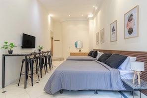 Ein Hotelzimmer mit Bett, Nachttisch, Lampe und Schreibtisch mit Stühlen.