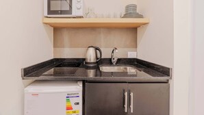 Eine kleine Küchenzeile mit Mikrowelle, Wasserkocher, Spüle und einem Schrank.