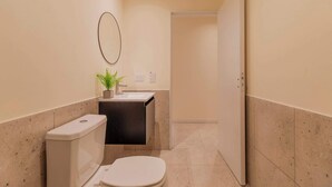 Ein schmales Badezimmer mit Toilette, Waschbecken und Spiegel.