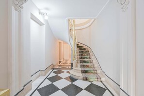 Eine Treppe mit gemusterten Läuferteppichen, einem Schachbrettfußboden und hellem Innenraum.