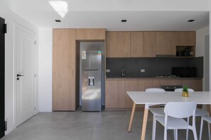 A modern kitchen with wooden cabinets, a stainless steel refrigerator, a black microwave, and a white dining table with chairs. - MOT Rentals + Black Ravignani 2C - 2 Bd Palermo Hollywood (Buenos Aires)